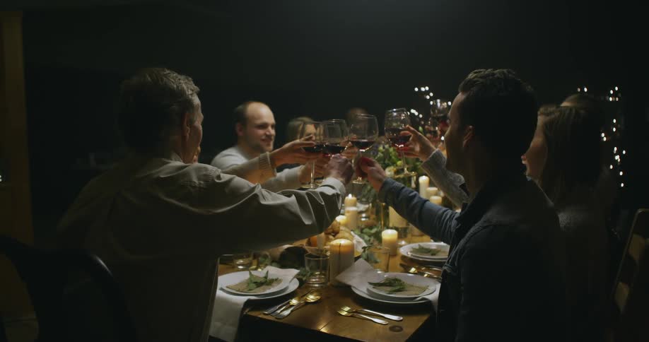 People at the table raise their wine glasses in a cheer