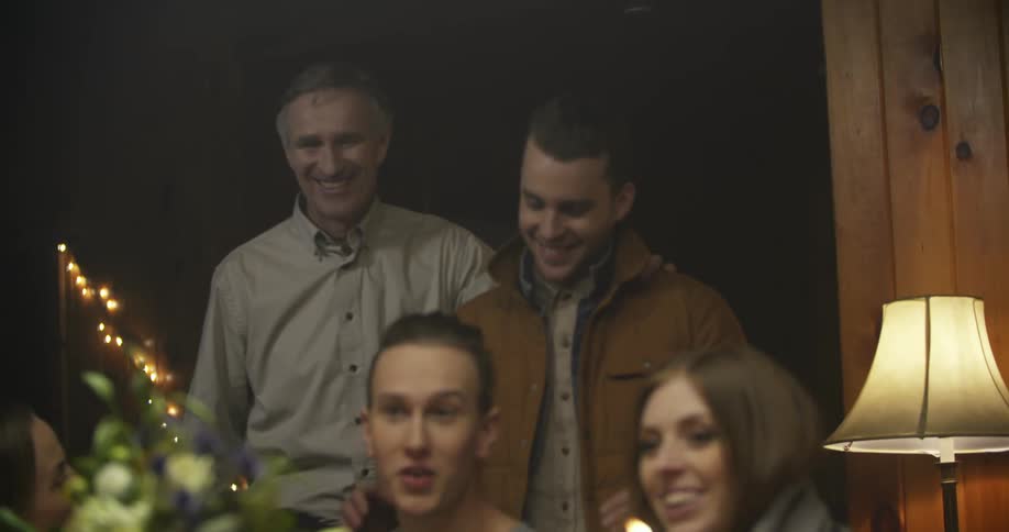 Two men walk into a holiday family gathering and one of the men hugs a woman
