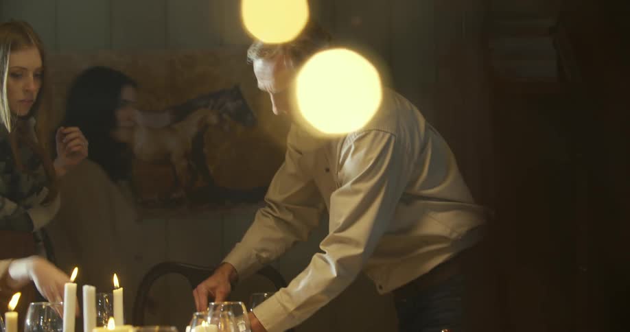 A man lights a candle with a lit candle at the dinner table