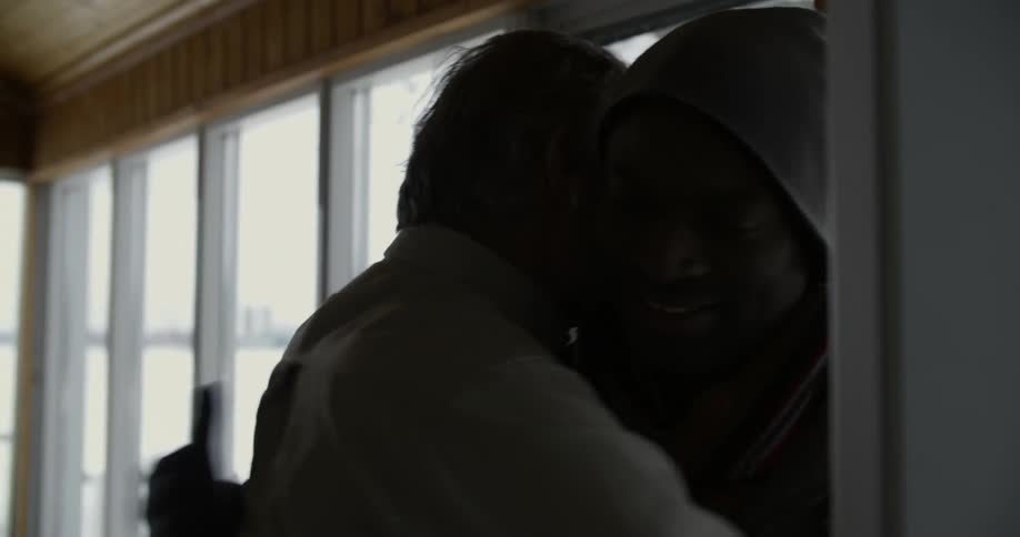 A man opens a door and smiles as he greets people