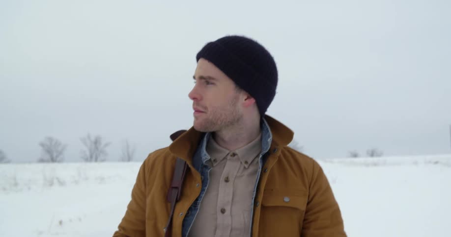 A man walks down a snowy country road in winter
