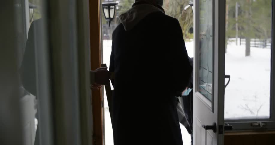 A man walks over to the door to greet some visitors