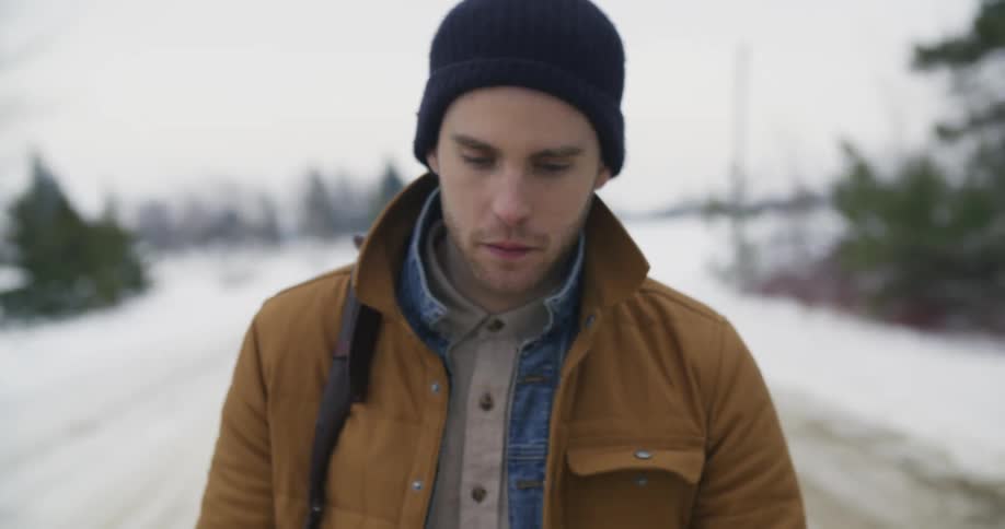 A man walks through a snowy and rural area