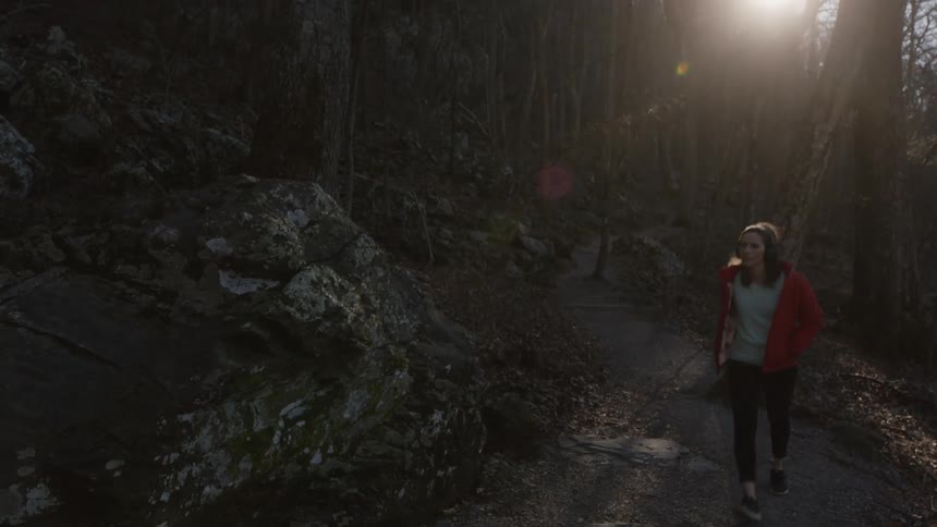A woman takes a peaceful stroll while listening to headphones in nature
