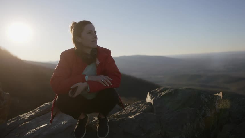 A woman puts her phone away to enjoy mountaintop view