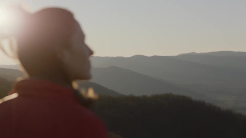 Woman takes off her headphones to enjoy scenic view on a sunny day