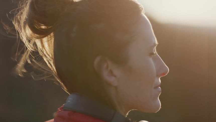 Woman takes off her headphones to enjoy windy morning outside