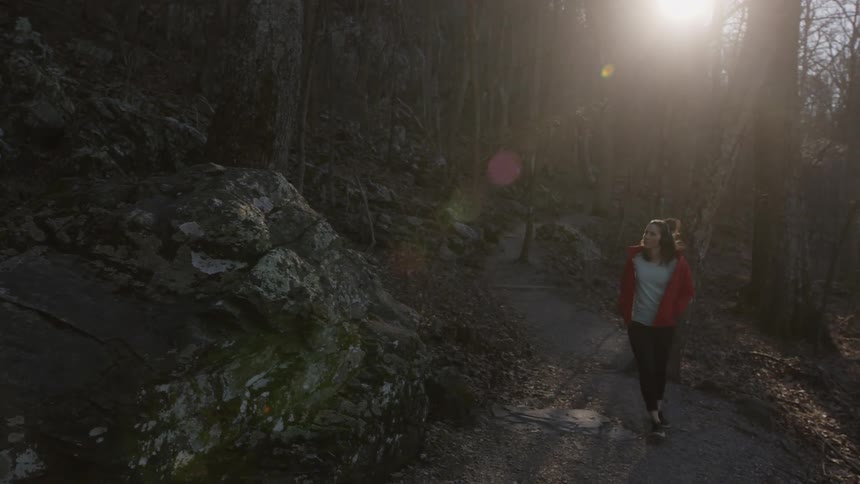 A woman bounces along on a nature trail listening to her headphones and taking in the beautiful autumn day