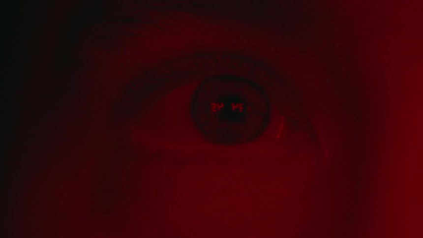 View of a persons eye moving and blinking as a red light shines on their face
