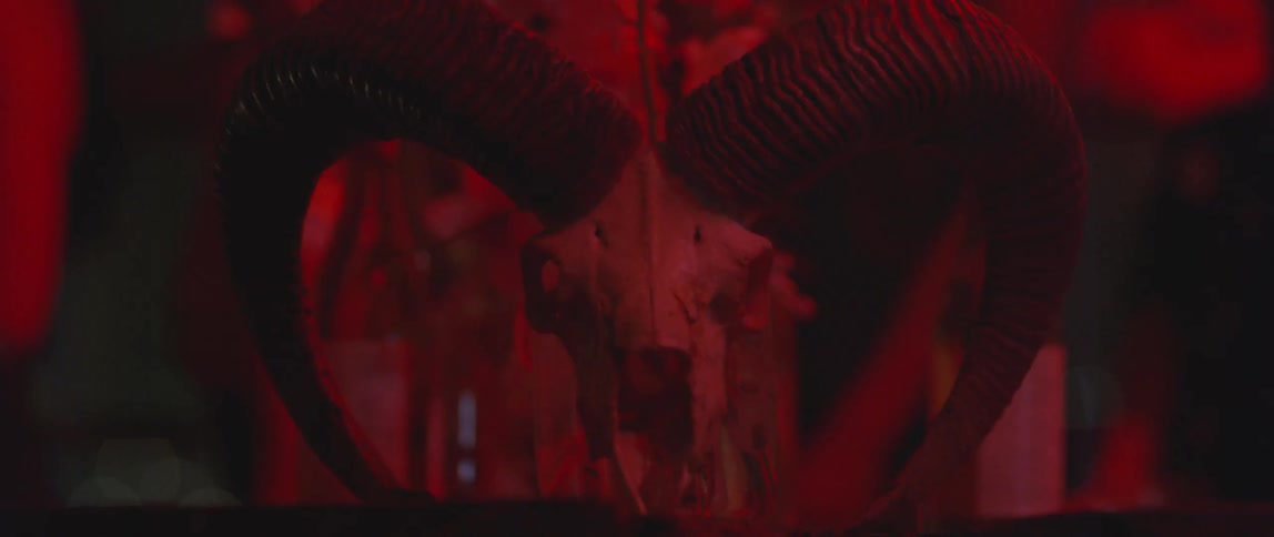 A skull with large horns coming off it has people behind it