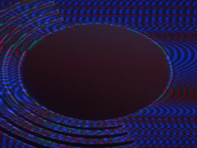 A red circle surrounded by blue static plays on a television screen