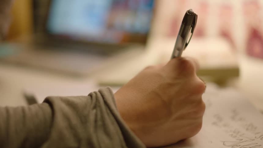 A hand holding a pen writing in a notebook