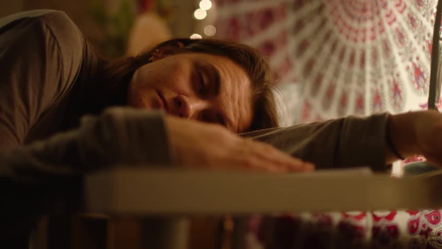 A woman rests her head on a table while lost in thought
