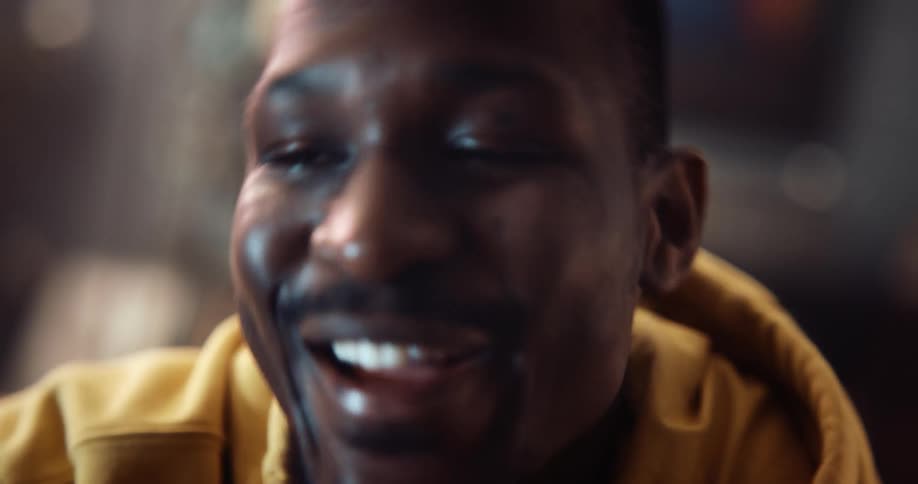 Man wearing hoodie smiles and laughs while talking