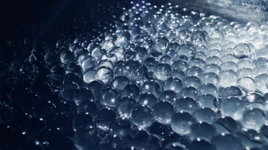 Light reflecting over translucent transparent glass spheres piled up inside a dimly lit room