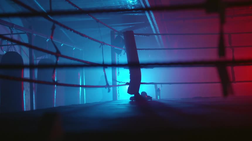 A boxer practices on punching bags in a boxing gym