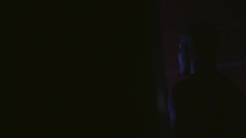A man is walking in the dark through a building toward a boxing ring