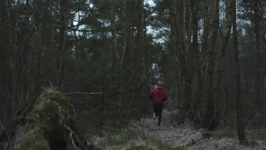 A man runs barefoot down a trail in the woods