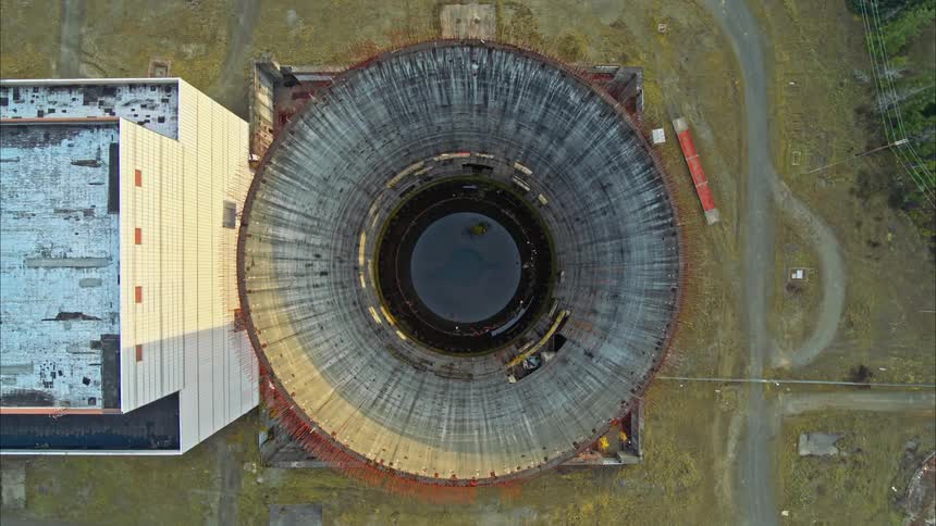 Aerial drone shot pointing down and flying out of partially complete nuclear reactor core