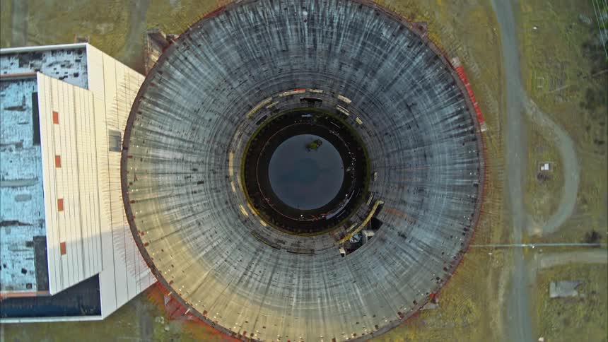 Aerial drone shot flying out the top of a partially complete nuclear reactor core