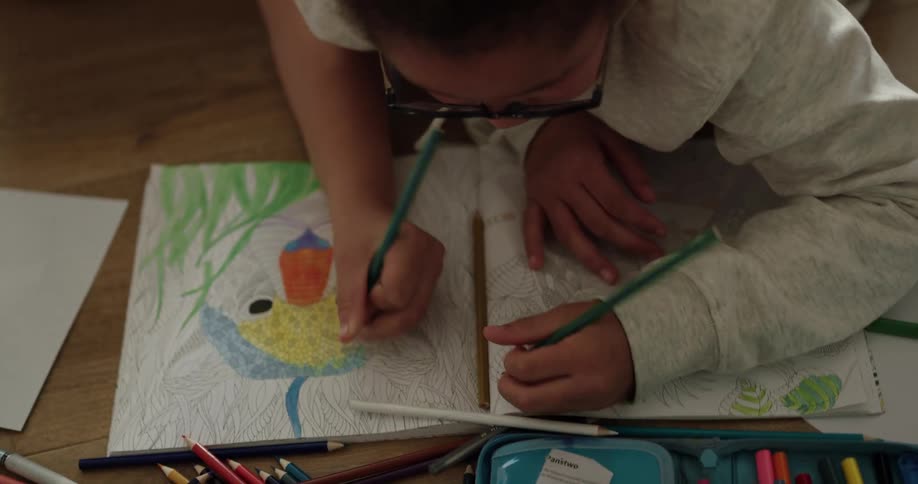 A young girl colors in a coloring book with her sister