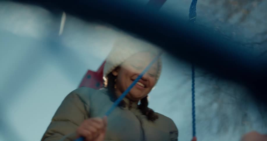 Girl pushing a swing on a playground on a clear winter day
