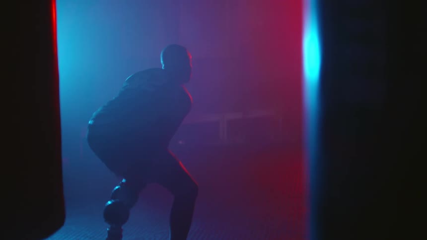 Man works with weight in dimly lit gym