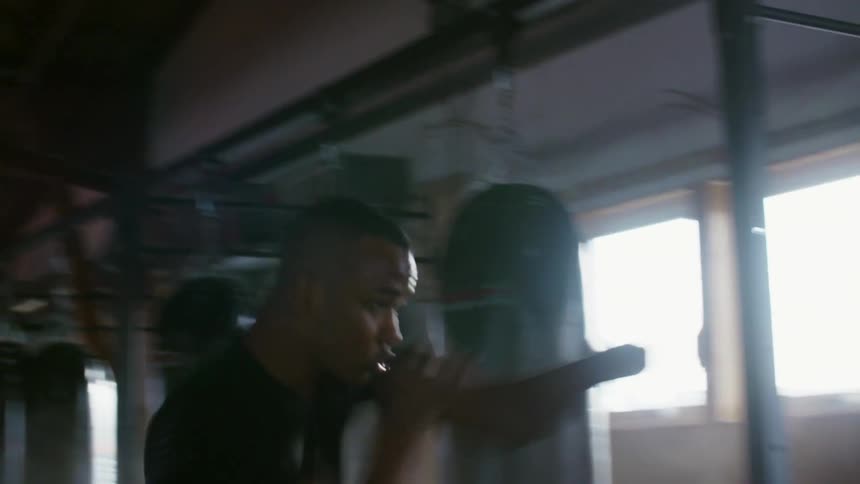 A man shadow boxes in a gym with a ring and heavy bags