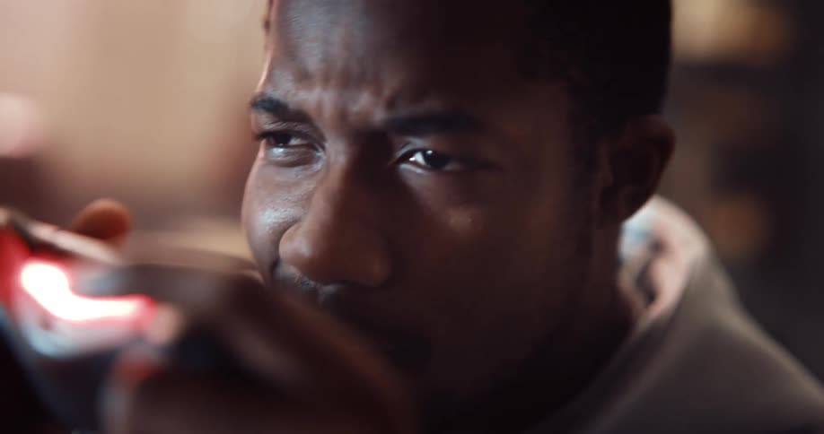 Close up of the face of a young man playing video games celebrating a victory
