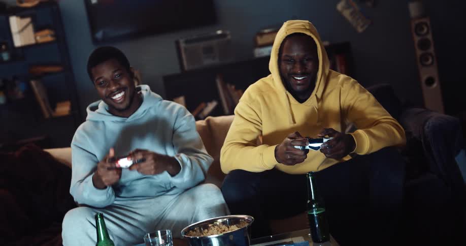 Two friends sitting playing video games laughing and joking around
