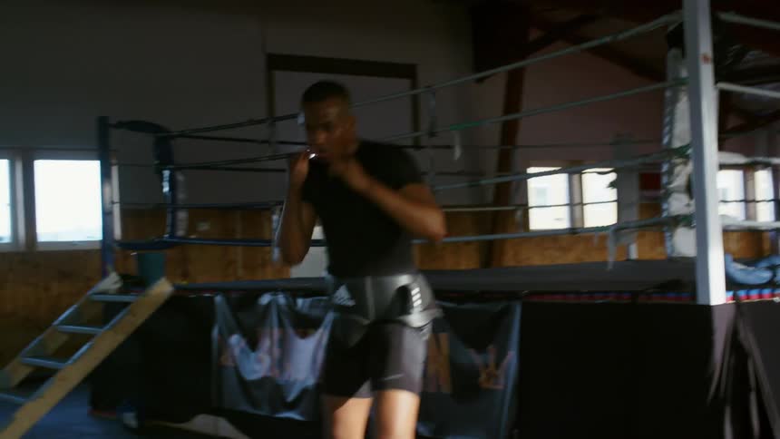 A boxer punches the air while training at a gym