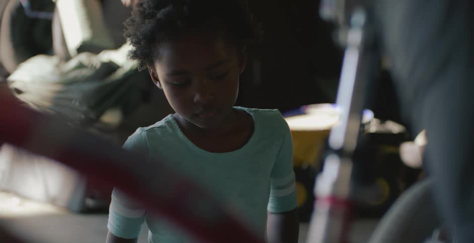 Girl smiles as parent repairs bicycle
