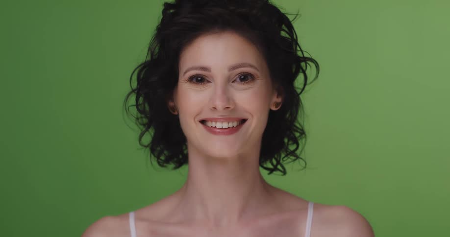 Woman poses smiling against a green background