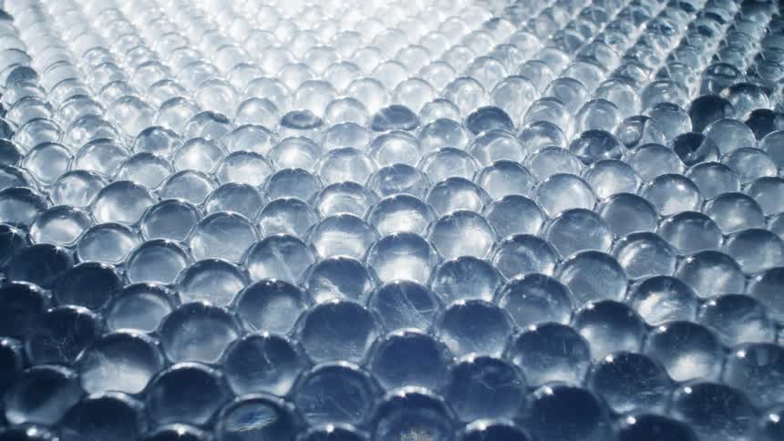 Water flowing under translucent transparent glass spheres piled up inside a dimly lit room