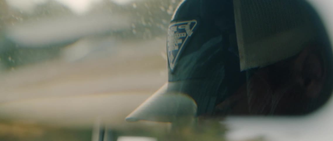 A man looks out the window as he drives past rural homes