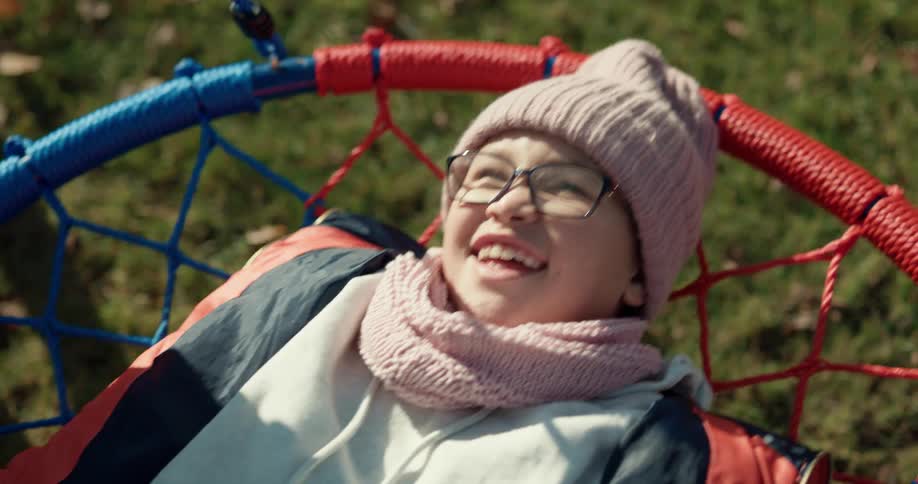 A young girl laughs as she plays on a swing