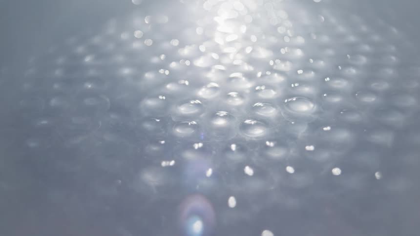 A bright light shines over tightly packed glass marbles