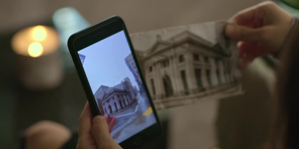 Person compares building in photograph to image on smartphone