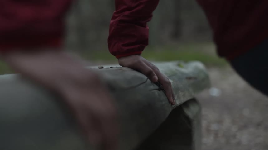 Person exercises using wooden furniture set near trail in park