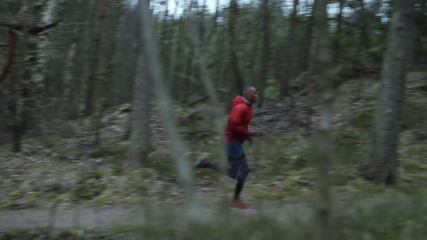 A man runs on a trail in a forest