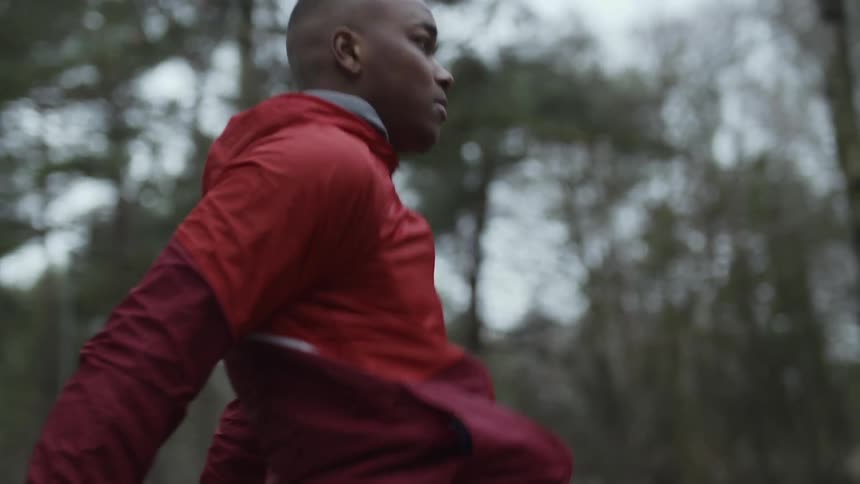 Young man wearing a red jacket exercising outdoors