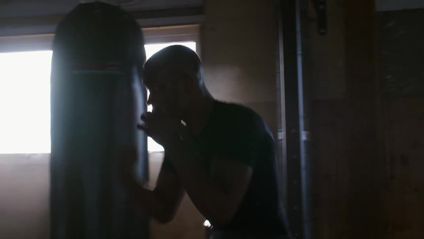 A man shadow boxes in a boxing gym during the day