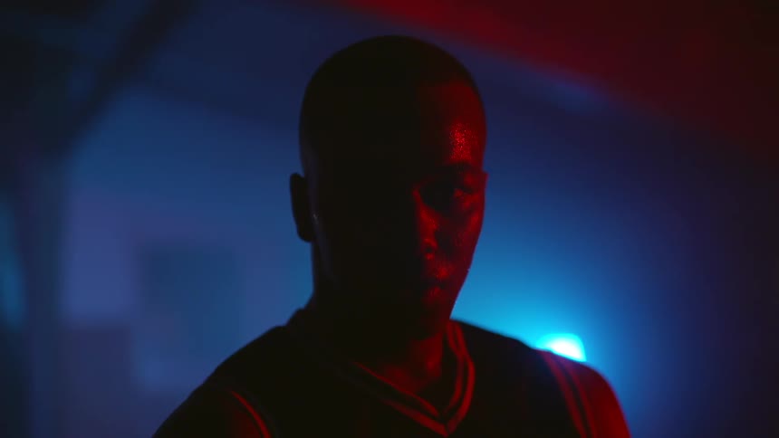 A man is standing in a dark room with one single light