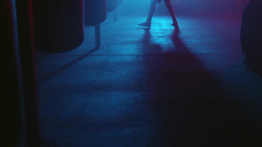 The legs of a man as he throws punches at a punching bag