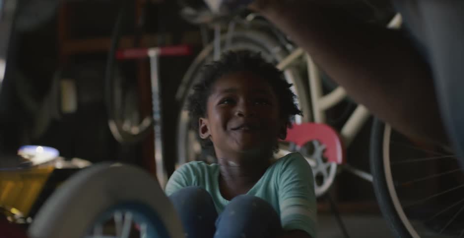 Father excitedly taking off his daughters bikes training wheels