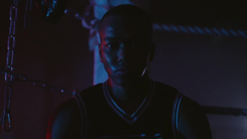 A man is sitting in the dark in a boxing ring