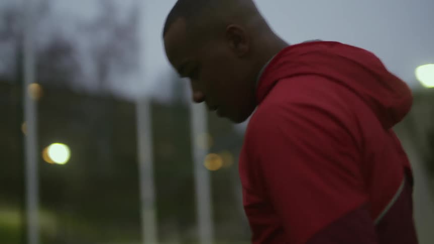 A man swings his arms around while stretching at a sports stadium