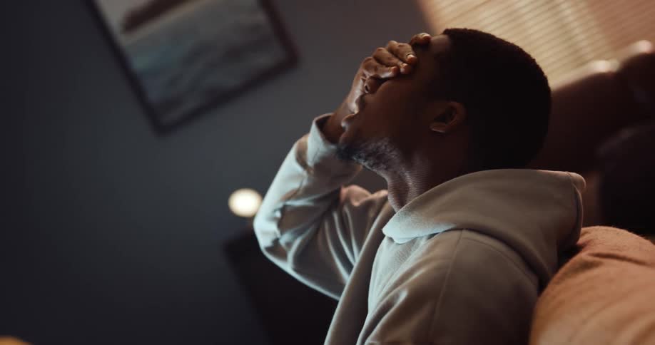 A man throws his head back in frustration while playing a video game with a friend