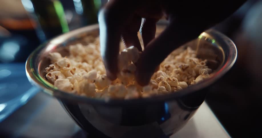 Two people eat popcorn drink beer and play video games
