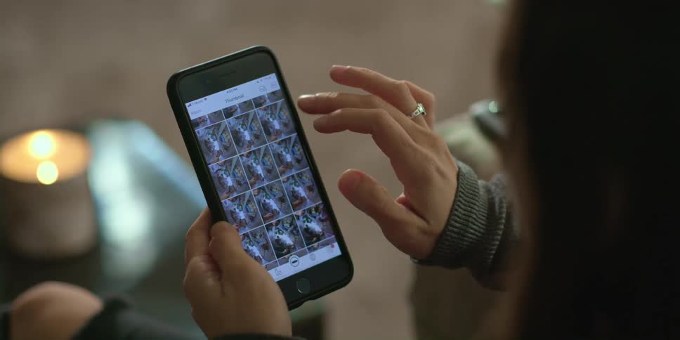 Woman sitting at home looks at the pictures taken on a smartphone